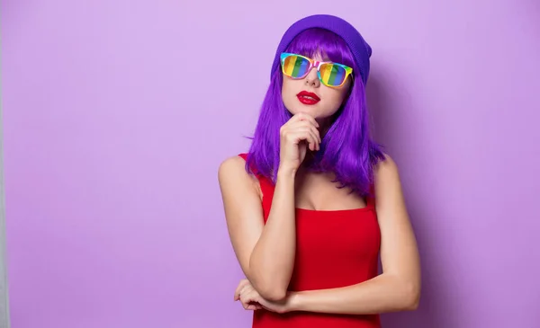 ピンクの背景に紫の髪と虹の眼鏡と若いスタイルの流行に敏感な女の子の肖像画 — ストック写真