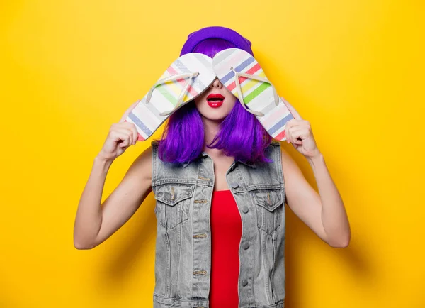 紫の髪型と若いスタイルの流行に敏感な女の子の肖像画は 黄色の背景にフリップフ ロップ靴を反転します — ストック写真