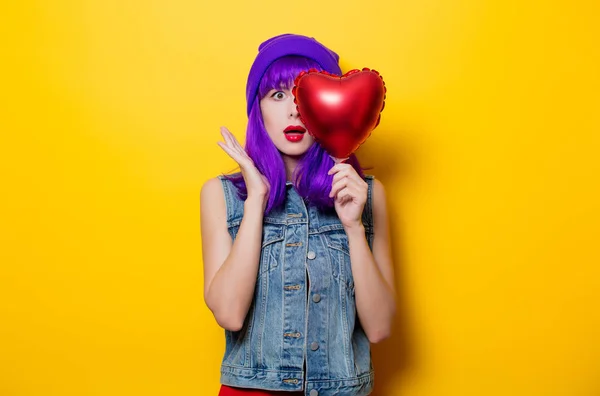 Portrait of young style hipster girl with purple hair and heart shape balloon on yellow background. St. Valentines Day Holiday