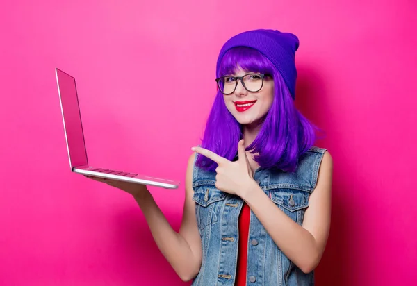 ピンクの背景に紫の髪とラップトップのコンピューターで若いスタイルの流行に敏感な女の子の肖像画 — ストック写真