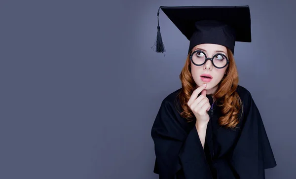 正方形学術キャップと灰色の背景にマントルで若い赤毛の大学院女の子 — ストック写真