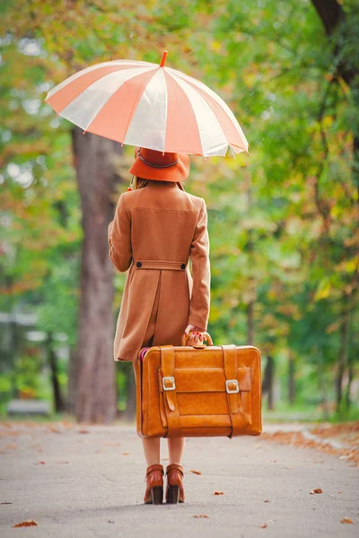 スーツケースと秋の公園で傘を持つ女性で背中側ビュー — ストック写真