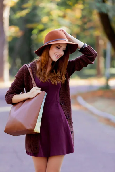 バッグと秋の公園屋外で帽子と若い赤毛の女性 — ストック写真