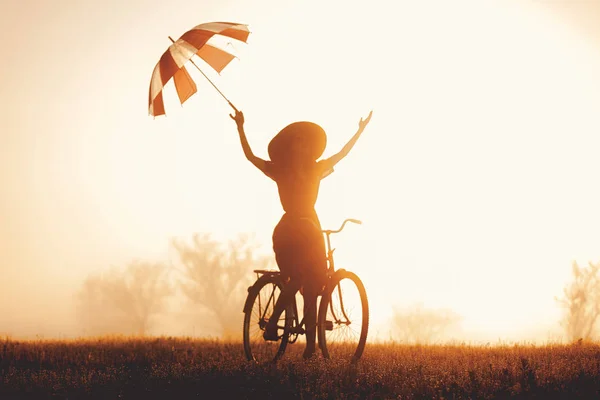 Fille avec parapluie chevauchant sur un vélo — Photo