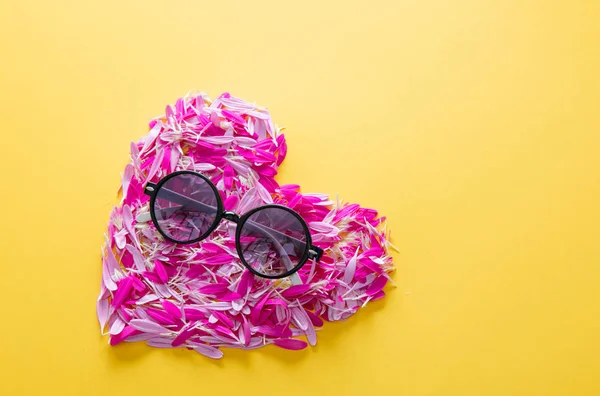 Ροζ και μοβ λουλούδι πέταλα σε σχήμα καρδιάς και γυαλιά ηλίου — Φωτογραφία Αρχείου