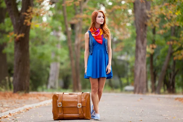 Junge schöne rothaarige Frau mit Koffer — Stockfoto