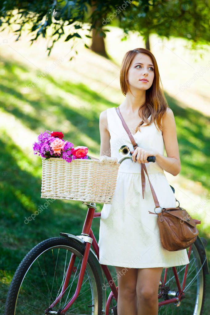 Young redhead girl with flowers in bike 