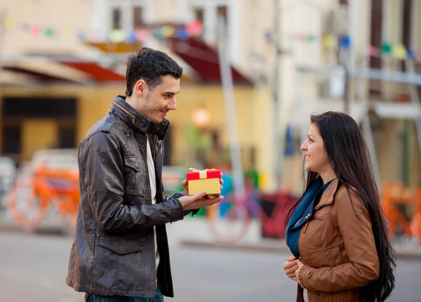 Jonge man geven een gift over een jong meisje — Stockfoto