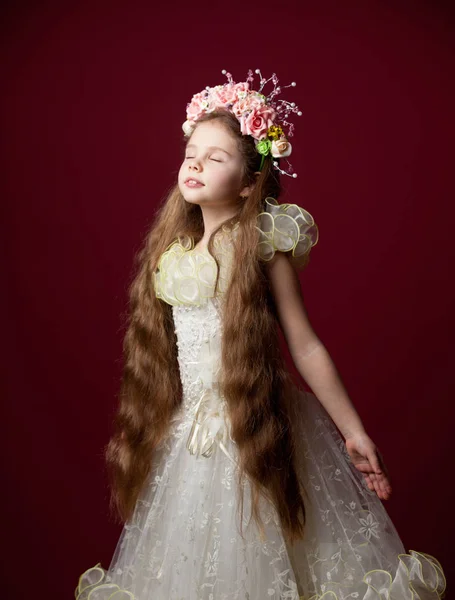 Mladá holčička v šatech s věncem na červeném pozadí — Stock fotografie
