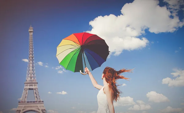 Молодая рыжая девушка с зонтом на фоне Эйфелевой башни — стоковое фото
