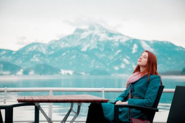 Genç Kızıl saçlı kız ceket yakınındaki gölde Alpler, Avusturya 