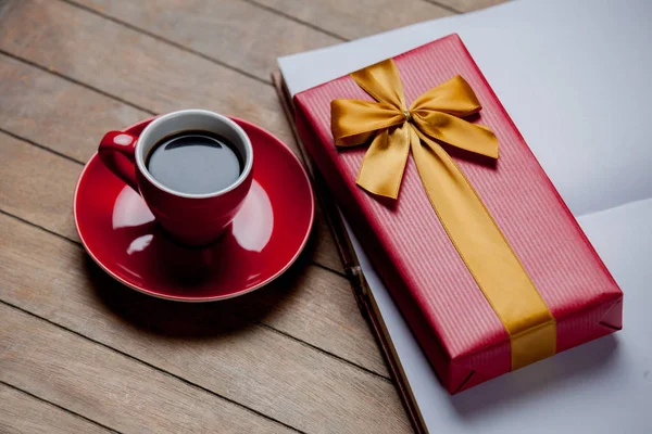 Cup of coffee with gift box on wooden background