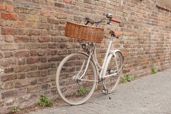 Белый велосипед с корзиной стоит у стены в Брюгге, Бельгия
 