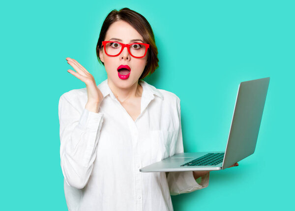 портрет красивой удивленной молодой женщины с ноутбуком на прекрасном зеленом фоне студии
