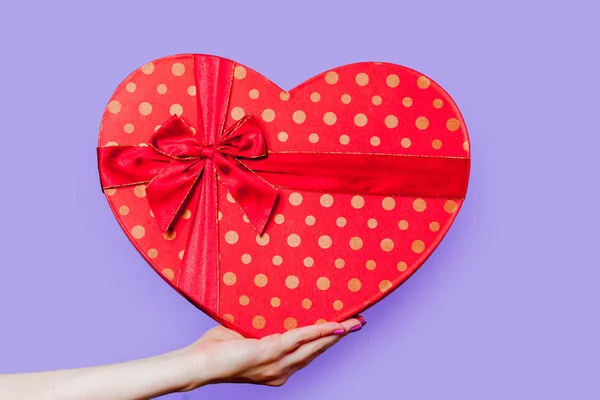 Female Hand Holding Heart Shape Box Bow Dots Purple Background — Stock Photo, Image