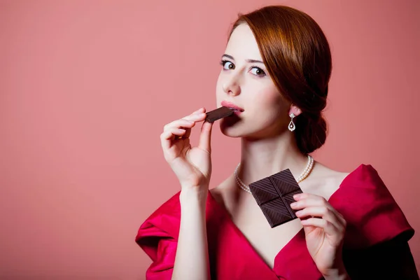 ピンクの背景にチョコレートで服を赤いビクトリア時代驚く女性 — ストック写真