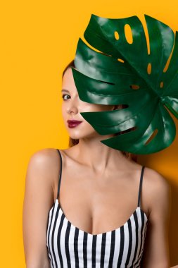 Palmiye yaprağı sarı renk arka plan üzerinde koyu giysili güzel kadın