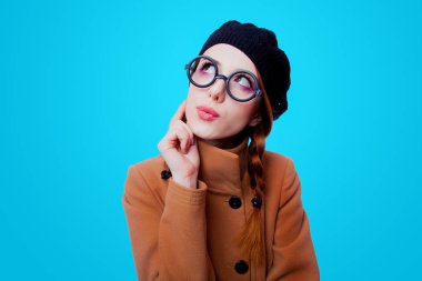 Gözlük ve kat üzerinde mavi arka plan ile genç redhead komik inek kız portresi 