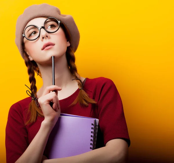 赤毛の若いオタク少女眼鏡と背景が黄色のベレー帽 — ストック写真