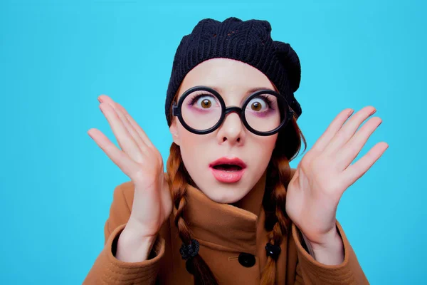 眼鏡と青の背景にコートを持つ若い赤毛面白いオタク少女の肖像画 — ストック写真