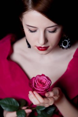 Genç kadın kırmızı Viktorya dönemi giysileri sürpriz koyu arka plan üzerinde kırmızı gül ile