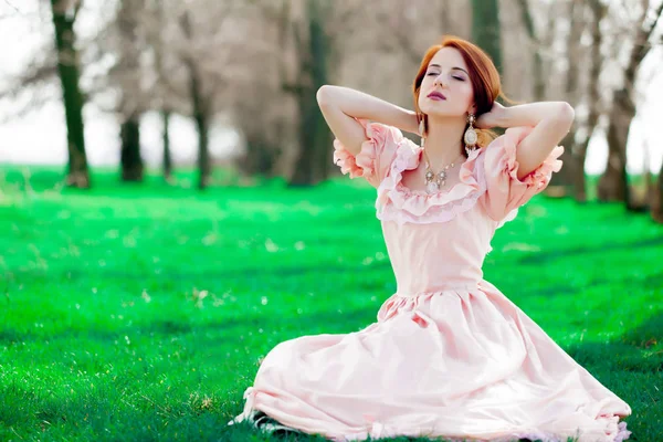 ビクトリア朝様式の若い Redheadd 少女の肖像画のドレス春の草の上に座って — ストック写真