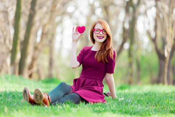 春には緑の草の上に座って若い赤毛の女の子の肖像画 — ストック写真