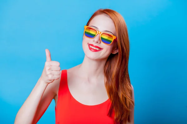 Rothaarige Mädchen Mit Regenbogen Sonnenbrille Auf Blauem Hintergrund — Stockfoto