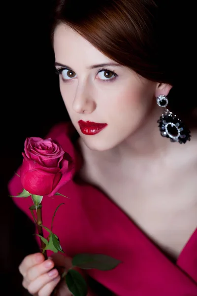 年轻惊奇的妇女在红色维多利亚时代衣裳与红色玫瑰色在黑暗的背景上 — 图库照片