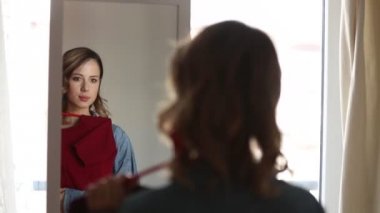 Kırmızı elbise elinde tutan ayna arayan genç güzel kadın