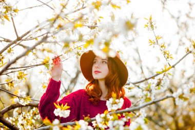 Kiraz çiçeği bahçe içinde kırmızı giysili Kızıl saçlı kızı