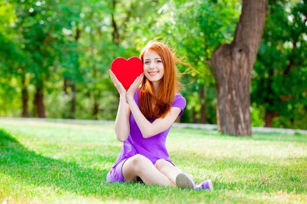 緑の夏の公園でハート形のおもちゃで若い赤毛の女の子 — ストック写真