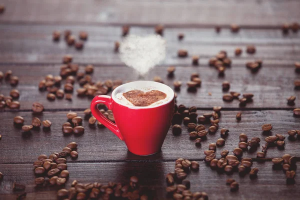 Röd Kopp Kaffe Med Hjärta Form Ånga Och Bönor Träbord — Stockfoto