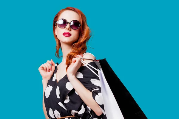 Rothaarige Frau Mit Sonnenbrille Und Einkaufstüten Auf Blauem Hintergrund — Stockfoto