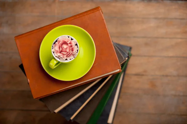 それと木製の背景に本の山にバラのつぼみのお茶のカップ ビューの上 — ストック写真