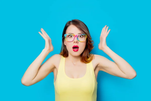 Roodharige Meisje Gele Jurk Gekleurde Bril Blauwe Achtergrond — Stockfoto