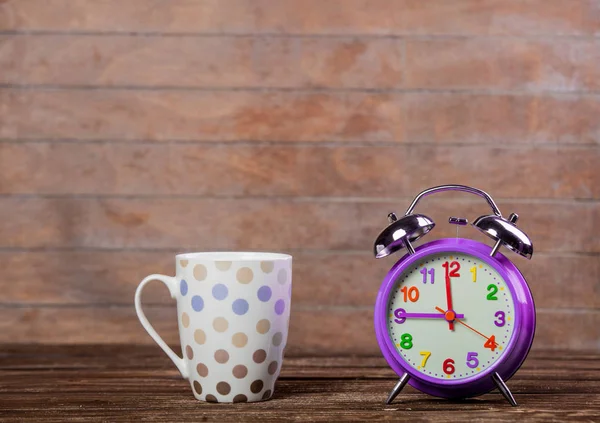 木製の背景に金属の目覚まし時計とコーヒーのカップ — ストック写真