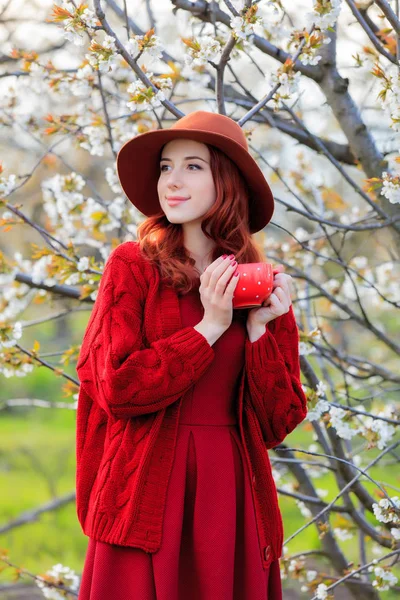 Roodharige Meisje Rode Kleding Hoed Kopje Koffie Poseren Cherry Blossom — Stockfoto