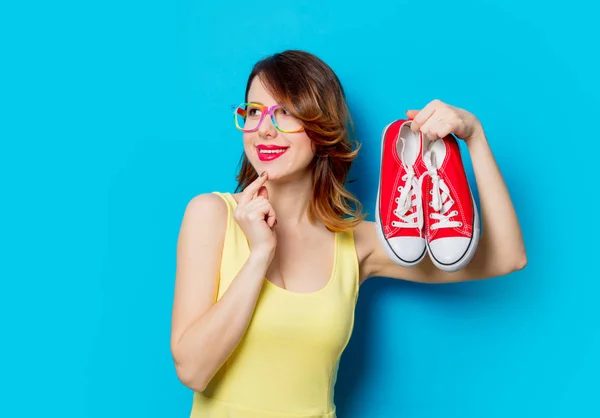 Roodharige Meisje Gele Jurk Gekleurde Glazen Gumshoes Blauwe Achtergrond Houden — Stockfoto