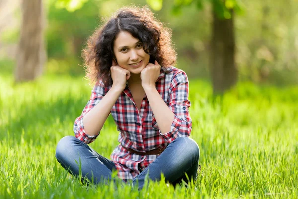 Młoda Dziewczyna Kręconymi Włosami Siedząc Trawie Parku — Zdjęcie stockowe