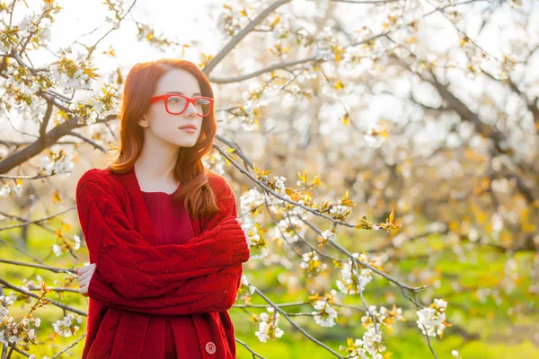 Redhead Dziewczyna Okularach Sobie Czerwoną Sukienkę Stojący Ogrodzie Kwiat Wiśni — Zdjęcie stockowe