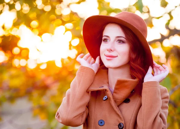时尚帽子和大衣的红发女孩在秋季户外散步 — 图库照片