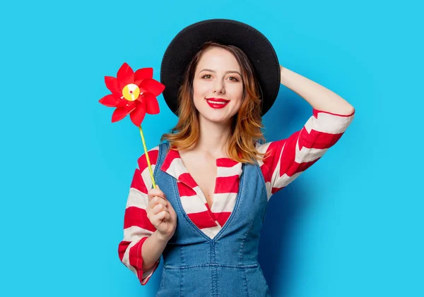 青の背景に風車 Poy と帽子とジーンズの服で赤毛の女の子 — ストック写真