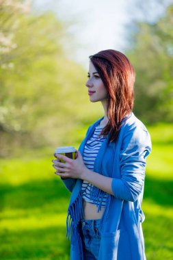 Kahve ya da çay bahar bahçesi ile mavi giysili genç kızı. Güneşli gün