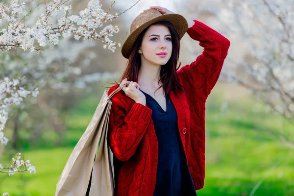春天盛开的绿色花园里戴着帽子和购物袋的年轻女孩 — 图库照片