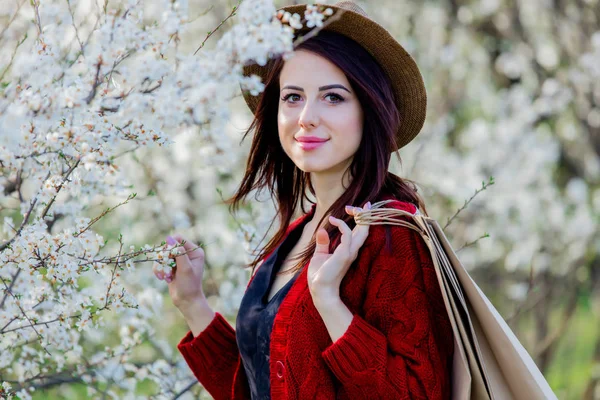 帽子と春の花グリーン ガーデンで買い物袋を持つ少女 — ストック写真