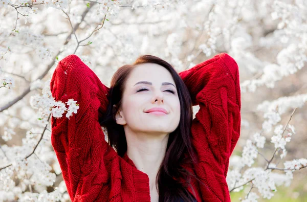 春の花の木ガーデンの赤いカーディガンの少女 — ストック写真