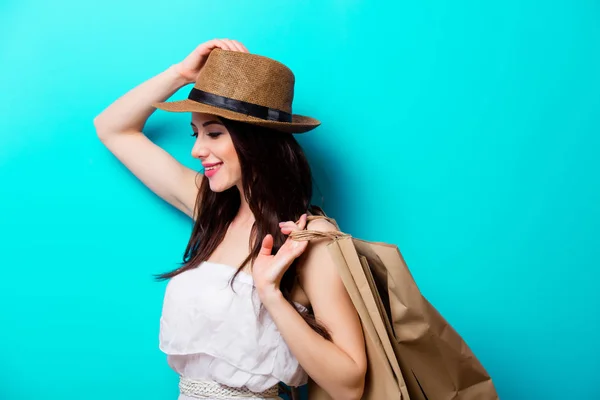 Junges Mädchen Mit Hut Und Einkaufstaschen Auf Blauem Hintergrund — Stockfoto