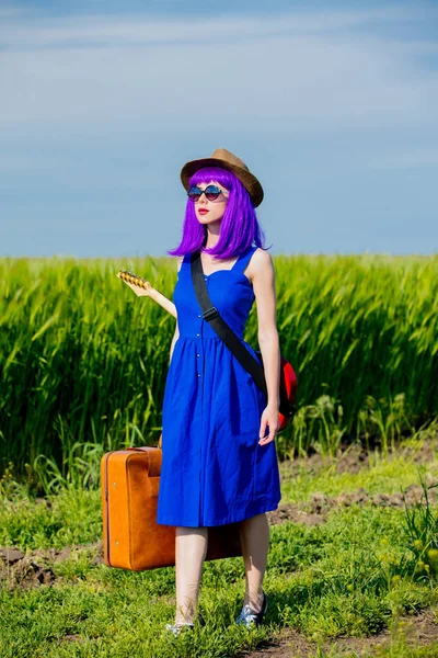 美丽的紫色头发女孩与手提箱和吉他在麦田在夏季季节 — 图库照片
