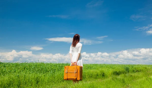 夏のシーズンの麦畑でスーツケースを持って美しい赤毛の女の子 — ストック写真